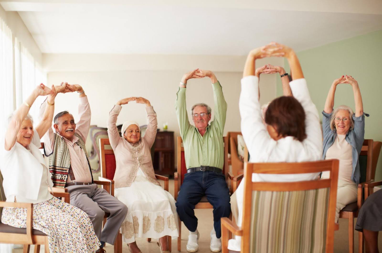 Group of seniors sitting in chairs participating in a guided group exercise session, representing a CILA program focused on care and support for adults with disabilities.